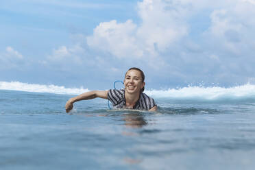 Glückliche Frau beim Schwimmen im Meer an einem sonnigen Tag - KNTF06779