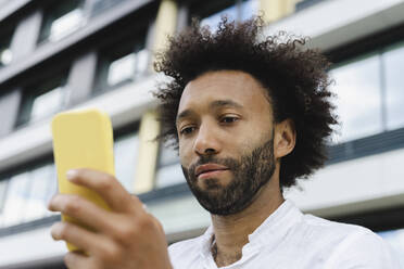 Mann mit lockigem Haar, der ein Mobiltelefon benutzt - SEAF01151