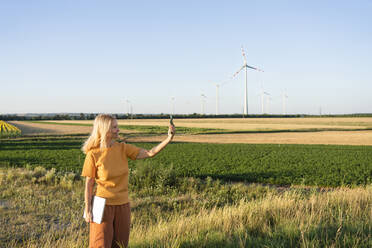 Woman taking selfie through smart phone standing in field - SVKF00414