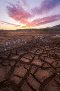 Arid ground covered with cracks located against cloudy sundown sky during drought in surroundings of Minas de Riotinto town in Spain - ADSF36074