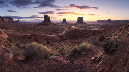 Atemberaubende Landschaft von Butte Felsformationen im Hochland mit Pfad während des Sonnenuntergangs in Monument Valley Navajo Tribal Park, Utah Arizona in USA - ADSF36079