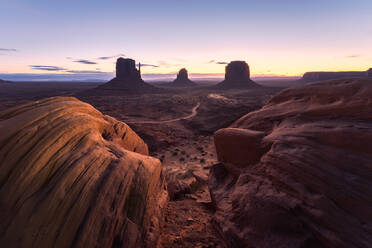 Atemberaubende Landschaft von Butte Felsformationen im Hochland mit Pfad während des Sonnenuntergangs in Monument Valley Navajo Tribal Park, Utah Arizona in USA - ADSF36082