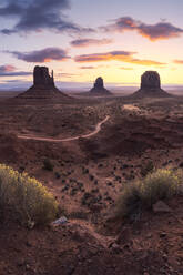 Atemberaubende Landschaft von Butte Felsformationen im Hochland mit Pfad während des Sonnenuntergangs in Monument Valley Navajo Tribal Park, Utah Arizona in USA - ADSF36083