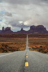 Atemberaubende Landschaft von Butte Felsformationen mit bewölktem Himmel in zwischen Asphalt Highway in Monument Valley Navajo Tribal Park, Utah Arizona in USA - ADSF36084