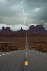 Atemberaubende Landschaft von Butte Felsformationen unter Gewitter Himmel mit Wolken in zwischen Asphalt Highway in Monument Valley Navajo Tribal Park, Utah Arizona in USA - ADSF36086