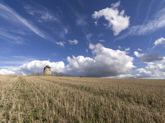 Windmill in a cropped field with a blue sky with white clouds, Normandy, France, Europe - RHPLF22624