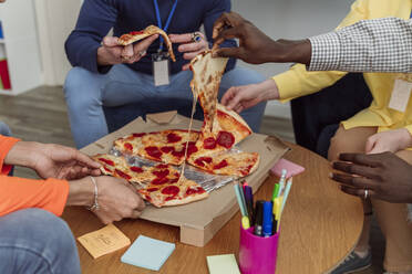 Hände von Geschäftskollegen halten Pizzastücke im Büro - OSF00607