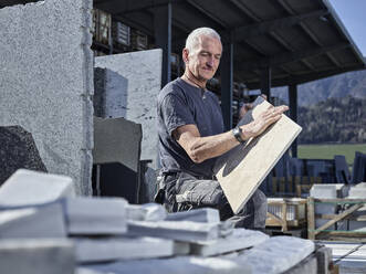 Älterer Steinmetz bei der Prüfung einer Steinplatte in der Werkstatt - CVF02075