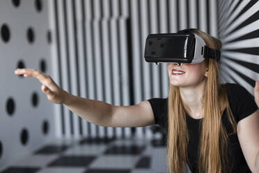 Smiling girl gesturing wearing virtual reality headset - LLUF00816