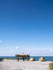 Woman sitting on bench near sea - LAF02774