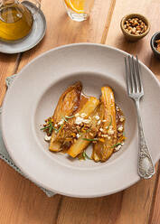 Top view of braised endives with orange juice on a wooden table next to a fork and different bowls - ADSF36152