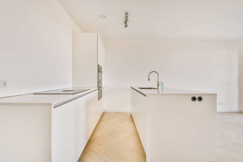 Innenraum einer leeren, offenen weißen Küche mit Holzparkettboden - ADSF36192