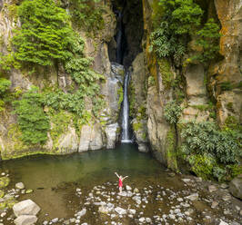 Luftaufnahme einer Frau beim Baden am Wasserfall Salto do Cabritol, Azoren, Portugal. - AAEF15158