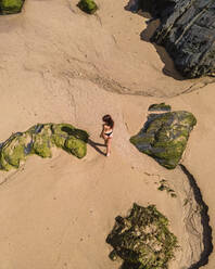 Aerial view of a beautiful woman on the beach at Playa de Serantes, Asturias, Spain. - AAEF15176