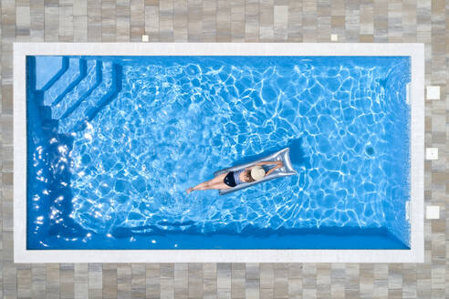 Woman lying on raft in swimming pool - MAEF13067