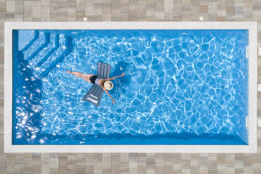Frau schwimmt mit Floß im Pool - MAEF13068