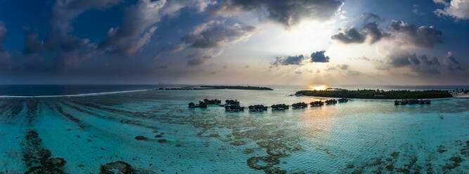 Malediven, Nord-Male-Atoll, Lankanfushi, Luftaufnahme des Indischen Ozeans bei Sonnenuntergang mit Bungalows der Ferienanlage im Hintergrund - AMF09558