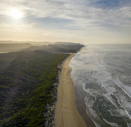 Luftaufnahme des Strandes und der Küstenlinie mit Wellen bei Sonnenuntergang und Wald, Knysna NU, Westkap, Südafrika. - AAEF15192