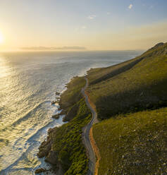 Luftaufnahme der Küstenstraße entlang der Küste von Koeel Bay mit Wellen bei Sonnenuntergang, Stadt Kapstadt NU, Westkap, Südafrika. - AAEF15204