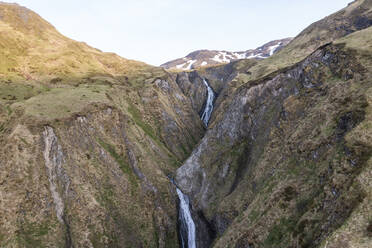 Luftaufnahme eines kleinen Flusses, der an einem Berg auf der Insel Unalaska, Alaska, Vereinigte Staaten, entlangfließt. - AAEF15306