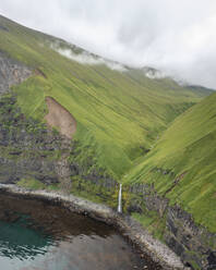 Luftaufnahme eines Wasserfalls an der Küste, Driftwood Bay, Insel Unalaska, Alaska, Vereinigte Staaten. - AAEF15318