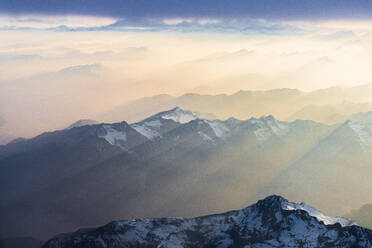 Flug über die schneebedeckten Gipfel der Lepontiner und Tessiner Alpen, beleuchtet von Sonnenstrahlen am romantischen Himmel bei Sonnenuntergang, Schweiz, Europa - RHPLF22687