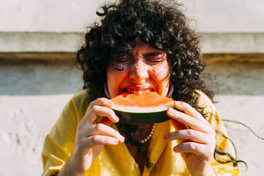Woman eating slice of watermelon on sunny day - MEUF07490