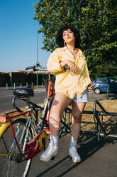 Confident woman with bicycle at parking station on sunny day - MEUF07492