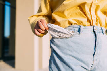 Woman showing empty pocket of jeans - MEUF07558