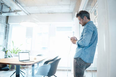 Businessman using smart phone in conference room at office - KNSF09562