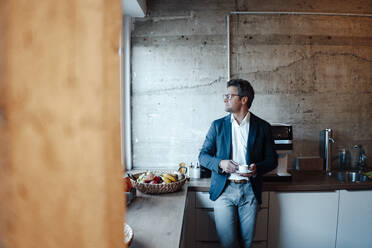 Älterer Geschäftsmann mit Kaffeetasse in einer Büro-Cafeteria - KNSF09583