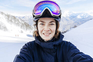 Smiling woman wearing ski goggles - OMIF01042