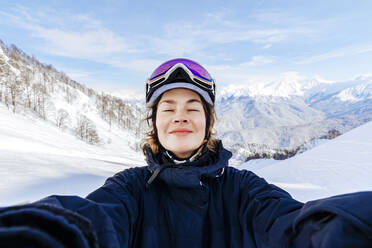 Woman with eyes closed enjoying in front of snowcapped mountains - OMIF01046