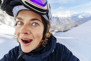 Surprised woman in front of snowy mountains - OMIF01047