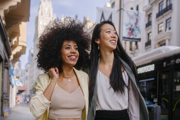 Smiling woman with friend strolling in city - MMPF00186