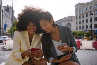 Multiracial friends sharing smart phones in city - MMPF00203