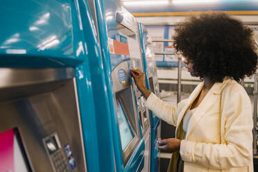 Frau mit Afrofrisur bei der Benutzung eines Fahrkartenautomaten in einer U-Bahn-Station - MMPF00216