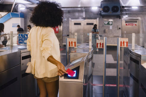 Frau scannt Fahrkarte am Drehkreuz in der U-Bahn-Station - MMPF00217