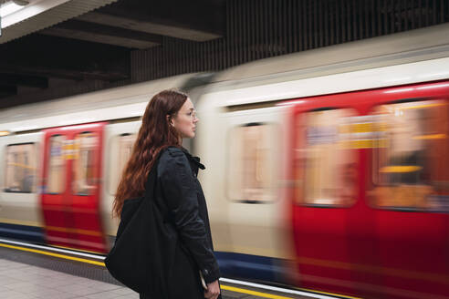 Young woman standing in front of subway at platform - PNAF04302