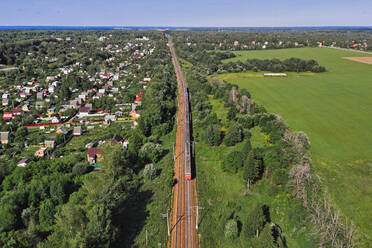 Luftaufnahme der Eisenbahnschienen, die sich am Rande einer ländlichen Stadt erstrecken, im Sommer - KNTF06791