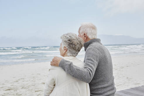 Senior couple standing on the beach with arms around - RORF02976