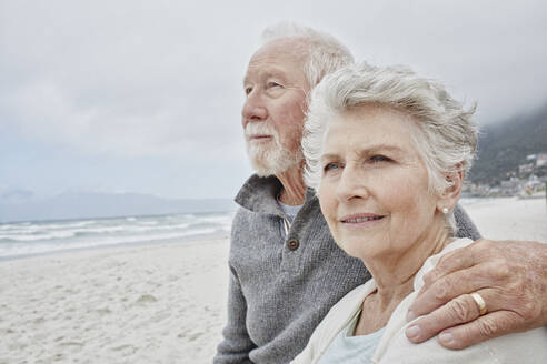 Senior couple standing on the beach with arms around - RORF02979