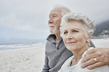 Senior couple standing on the beach with arms around - RORF02980