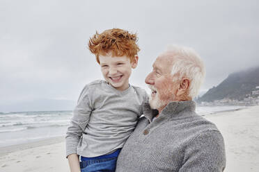 Happy grandfather carrying his grandson at the sea - RORF02984