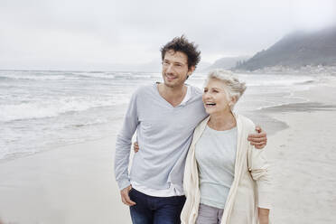 Mature man walking on the beach embracing his mother - RORF03000