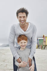 Lachender Vater und Sohn an einem windigen Strand - RORF03002