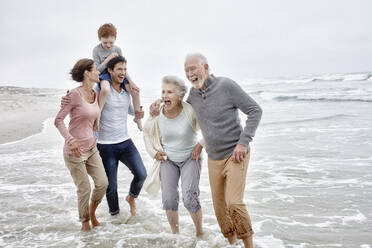 Happy couple spending quality time at the beach with son and grandparents - RORF03008