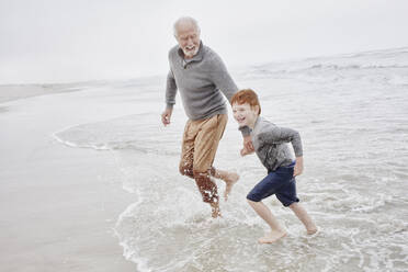 Grandfather playing with grandson at the sea - RORF03025