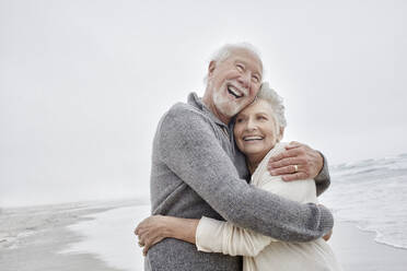 Laughing senior couple embracing at the sea - RORF03026