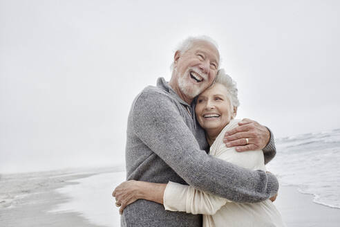 Laughing senior couple embracing at the sea - RORF03026